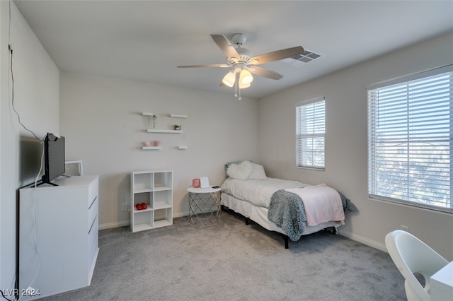 bedroom featuring ceiling fan, light colored carpet, and multiple windows