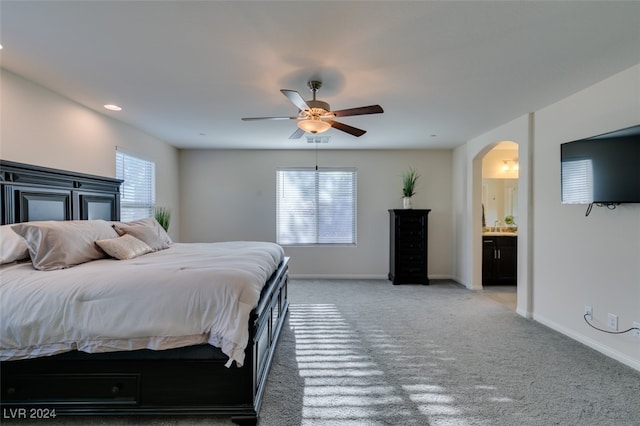 bedroom with ensuite bath, ceiling fan, and carpet