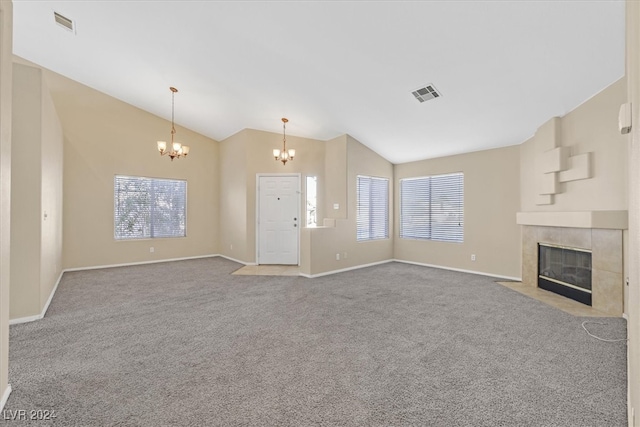 unfurnished living room with a chandelier, carpet, vaulted ceiling, and a tile fireplace