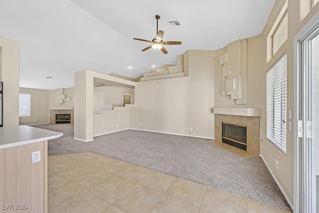 unfurnished living room featuring ceiling fan, a fireplace, light tile patterned floors, and high vaulted ceiling