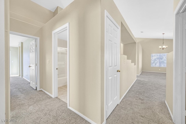 hall with light carpet and an inviting chandelier