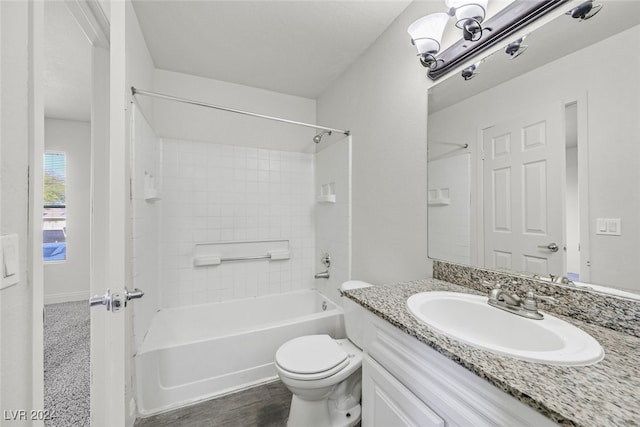 full bathroom featuring hardwood / wood-style flooring, vanity, tiled shower / bath combo, and toilet