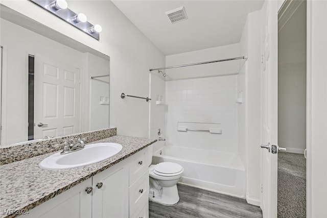 full bathroom featuring washtub / shower combination, hardwood / wood-style floors, vanity, and toilet