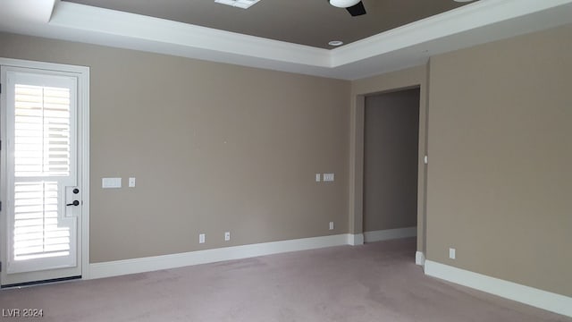 unfurnished room with ceiling fan, ornamental molding, light carpet, and a tray ceiling