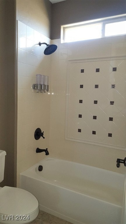 bathroom with toilet and tiled shower / bath