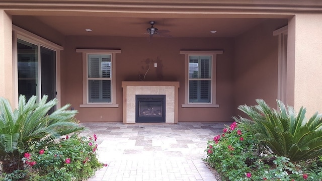 view of patio / terrace featuring ceiling fan and a tiled fireplace