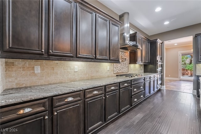 2804 Josephine Dr, Henderson, NV 89044 - kitchen with wall chimney range hood, appliances with stainless steel finishes, dark brown cabinetry, light stone countertops, and baseboards