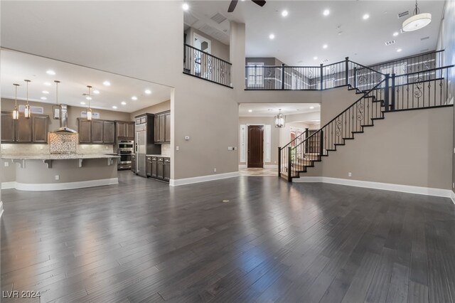 2804 Josephine Dr, Henderson, NV 89044 - unfurnished living room with a ceiling fan, stairs, dark wood-type flooring, baseboards, and a towering ceiling