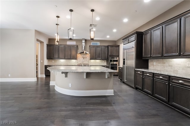 2804 Josephine Dr, Henderson, NV 89044 - kitchen with wall chimney exhaust hood, dark brown cabinetry, an island with sink, backsplash, and appliances with stainless steel finishes