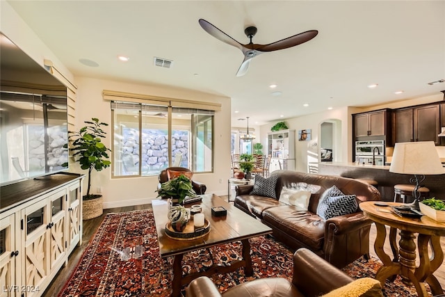 living room featuring ceiling fan and dark wood-type flooring