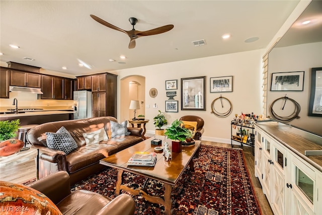 living room featuring ceiling fan, wood-type flooring, and sink