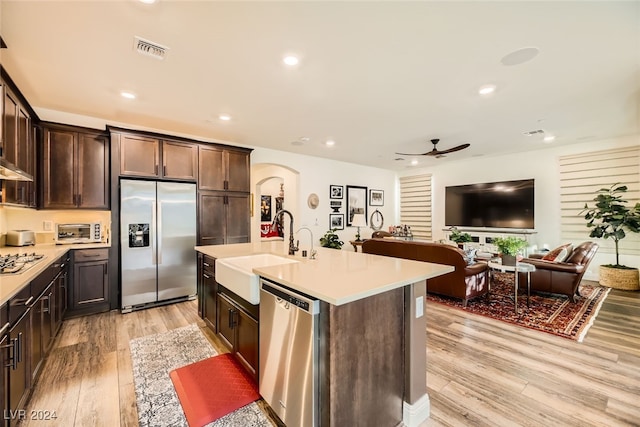 kitchen with a center island with sink, sink, ceiling fan, light hardwood / wood-style floors, and stainless steel appliances