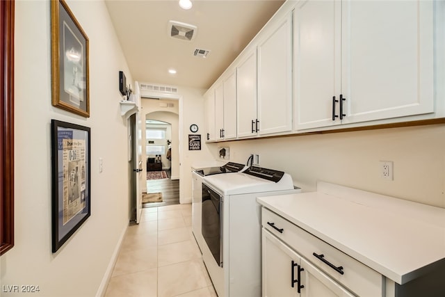 laundry room featuring cabinets, light tile patterned floors, and washing machine and dryer