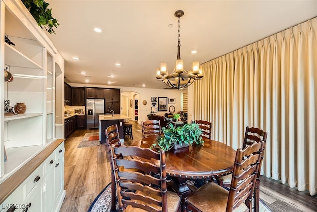 dining room featuring sink, light hardwood / wood-style flooring, and an inviting chandelier