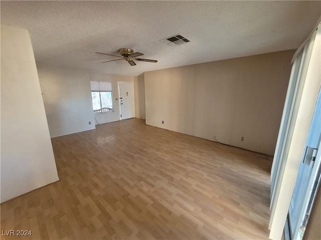 spare room with a textured ceiling, ceiling fan, and light hardwood / wood-style flooring