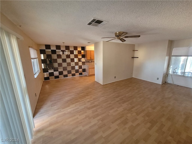 unfurnished living room featuring light wood-type flooring, a textured ceiling, and ceiling fan