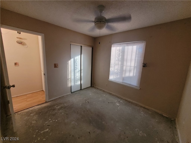 unfurnished bedroom featuring ceiling fan, concrete flooring, a textured ceiling, and a closet