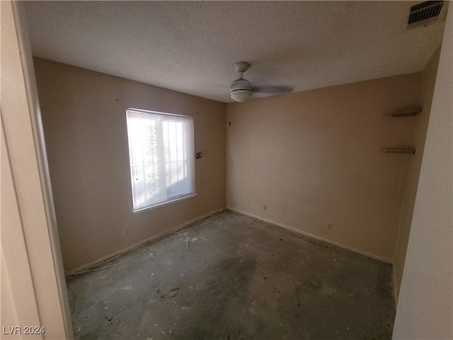 unfurnished room with ceiling fan, concrete flooring, and a textured ceiling