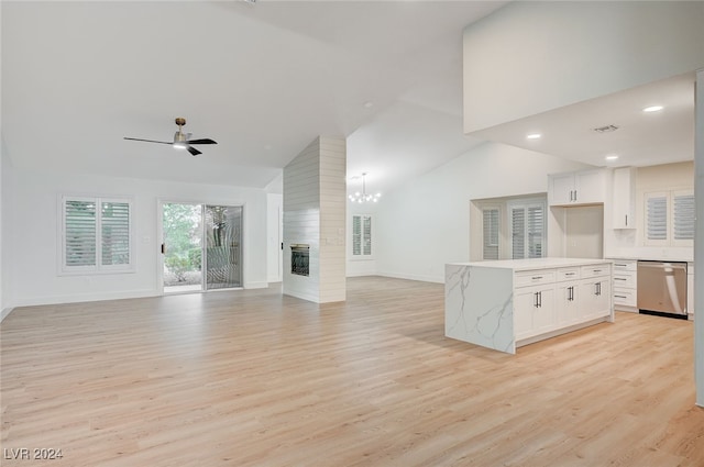 unfurnished living room with ceiling fan with notable chandelier, a large fireplace, light wood-type flooring, and high vaulted ceiling