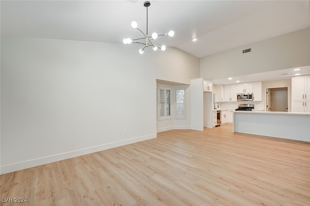 unfurnished living room with light wood-type flooring, sink, high vaulted ceiling, and a chandelier