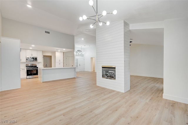 unfurnished living room featuring a chandelier, a large fireplace, and light hardwood / wood-style floors