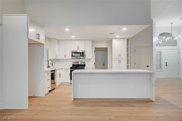 kitchen with white cabinetry, light hardwood / wood-style flooring, pendant lighting, and appliances with stainless steel finishes