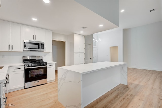 kitchen featuring light wood-type flooring, appliances with stainless steel finishes, a center island, and white cabinetry