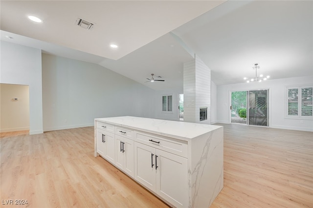 kitchen with light stone countertops, light wood-type flooring, ceiling fan with notable chandelier, vaulted ceiling, and white cabinets