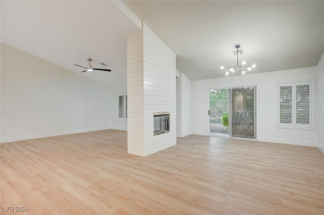 unfurnished living room featuring a fireplace, high vaulted ceiling, light hardwood / wood-style floors, and ceiling fan with notable chandelier