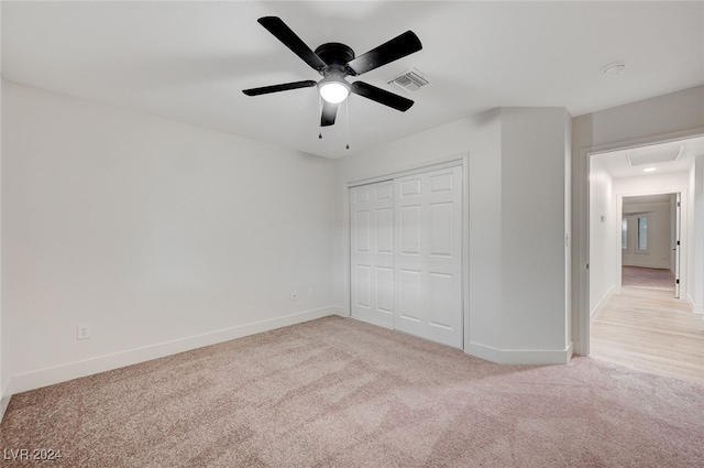 unfurnished bedroom with light carpet, a closet, and ceiling fan