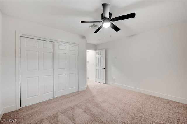 unfurnished bedroom featuring light carpet, a closet, and ceiling fan