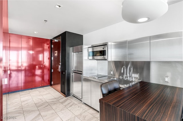 kitchen featuring tasteful backsplash, black electric cooktop, and sink