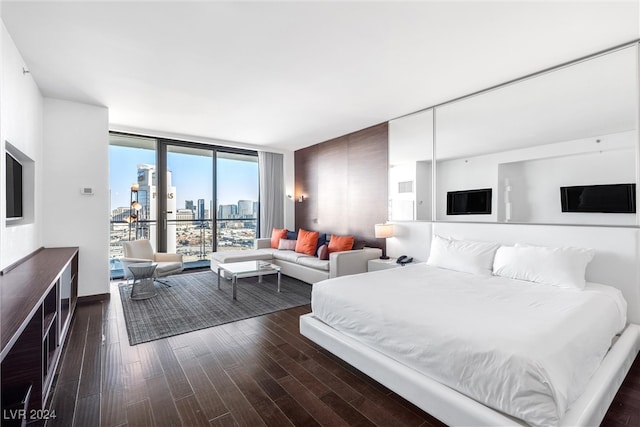 bedroom with access to exterior, dark hardwood / wood-style floors, and a wall of windows