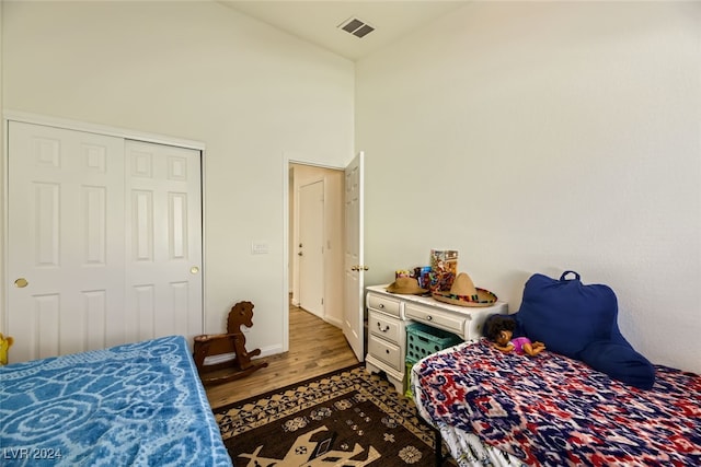 bedroom with dark wood-type flooring, high vaulted ceiling, and a closet