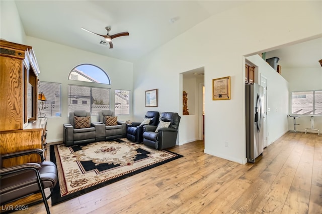 living room with ceiling fan, light hardwood / wood-style floors, and high vaulted ceiling