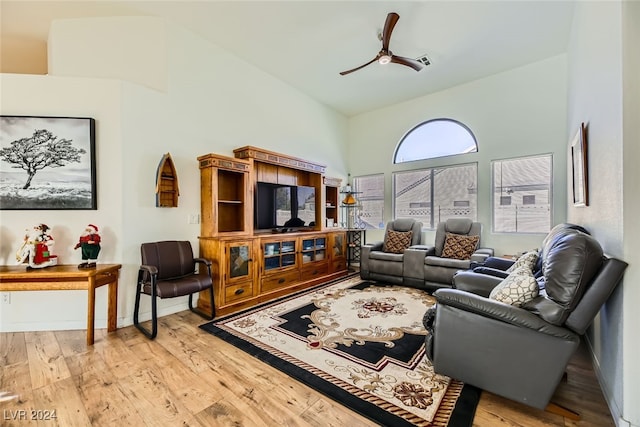 living room with ceiling fan, light wood-type flooring, and high vaulted ceiling