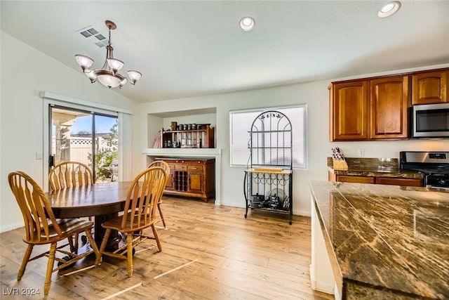 dining area with a chandelier, light wood-type flooring, and vaulted ceiling