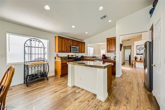 kitchen with lofted ceiling, sink, light wood-type flooring, appliances with stainless steel finishes, and a kitchen island