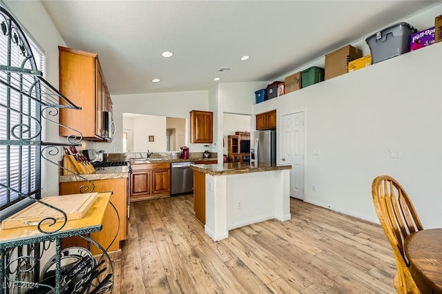 kitchen featuring sink, appliances with stainless steel finishes, lofted ceiling, a kitchen island, and light wood-type flooring