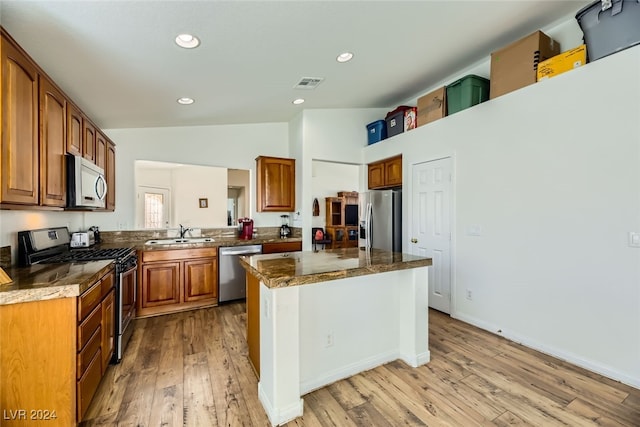 kitchen featuring a center island, sink, dark stone countertops, light hardwood / wood-style floors, and stainless steel appliances