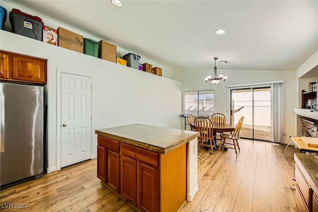 kitchen featuring light wood-type flooring, vaulted ceiling, decorative light fixtures, an inviting chandelier, and stainless steel refrigerator