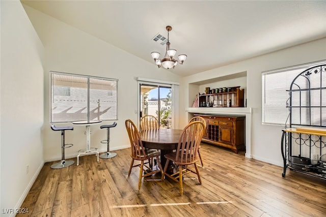 dining room with light hardwood / wood-style floors, lofted ceiling, and a notable chandelier