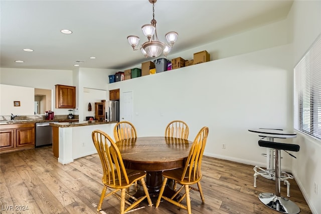 dining area featuring a chandelier, light hardwood / wood-style flooring, lofted ceiling, and sink