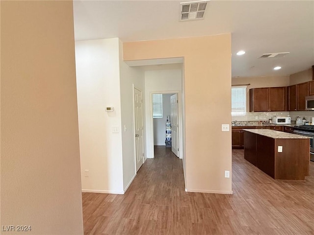 kitchen with tasteful backsplash, a kitchen island, light hardwood / wood-style floors, and appliances with stainless steel finishes