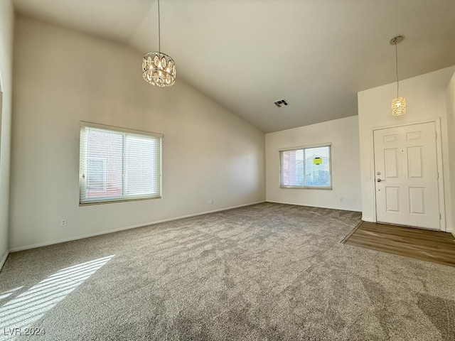 unfurnished living room featuring carpet flooring, an inviting chandelier, and high vaulted ceiling