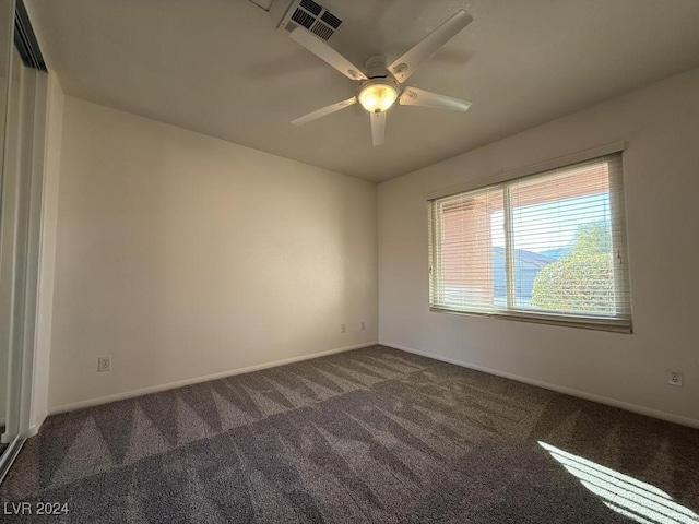 empty room featuring ceiling fan and dark colored carpet