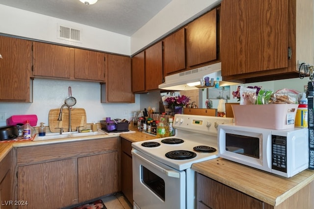 4740 Corsaire Ave, Las Vegas, NV 89115 - kitchen featuring white appliances, a sink, light countertops, under cabinet range hood, and brown cabinets