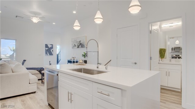 kitchen featuring pendant lighting, white cabinetry, stainless steel appliances, sink, and a center island with sink