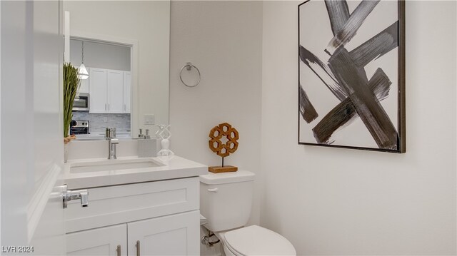 bathroom with toilet, vanity, and tasteful backsplash