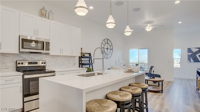 kitchen featuring an island with sink, appliances with stainless steel finishes, backsplash, white cabinets, and sink